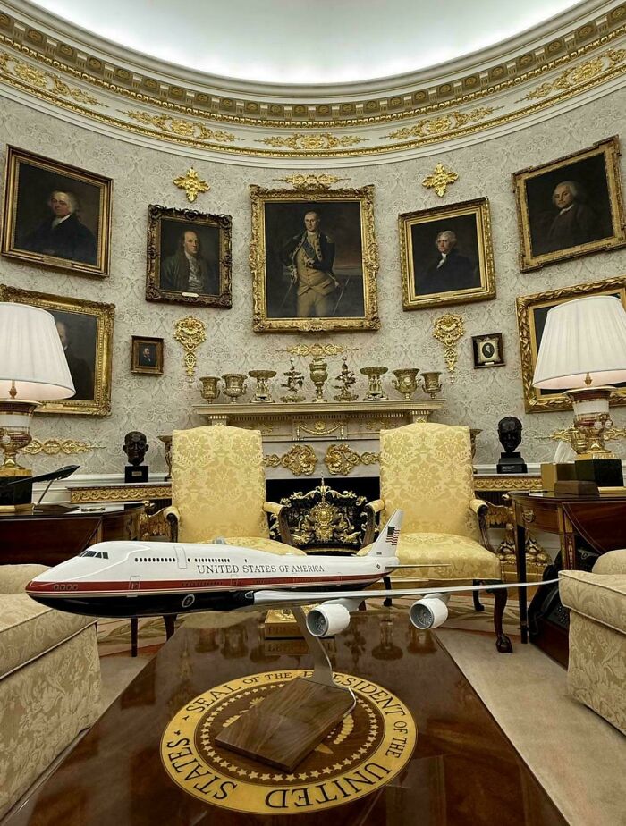 Model airplane on ornate coffee table in an opulent room with vintage portraits and classic home decor elements.
