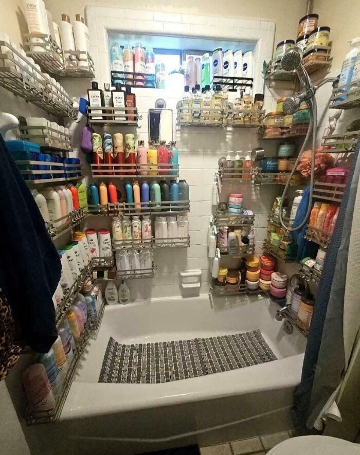 Bathroom bathtub overloaded with ridiculous home decor and DIY storage racks holding numerous bottles and containers.