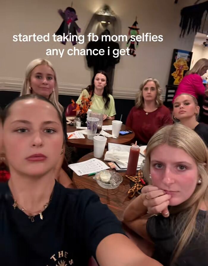 Group of women posing for unposed chaotic mom selfies at a restaurant, capturing the hectic energy of a mom on social media.