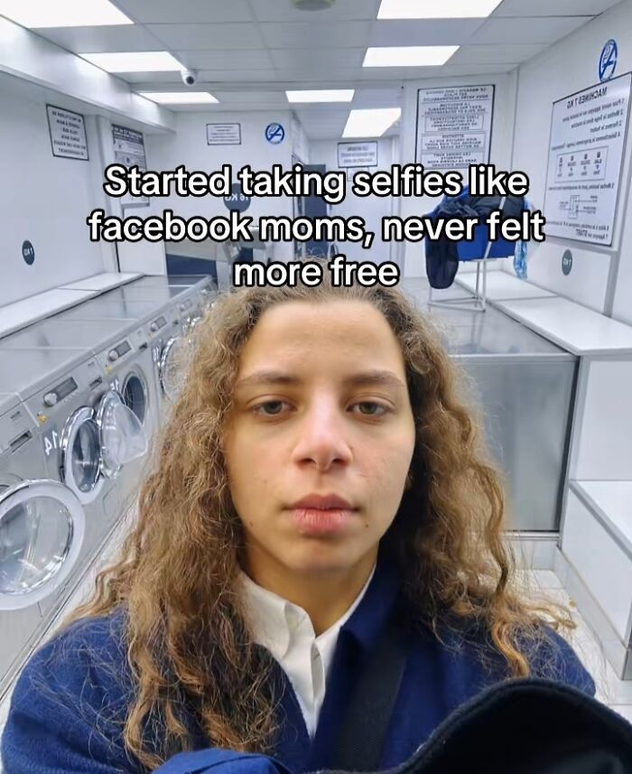 Young woman taking a selfie in a laundromat, capturing the chaotic energy of a mom on social media.
