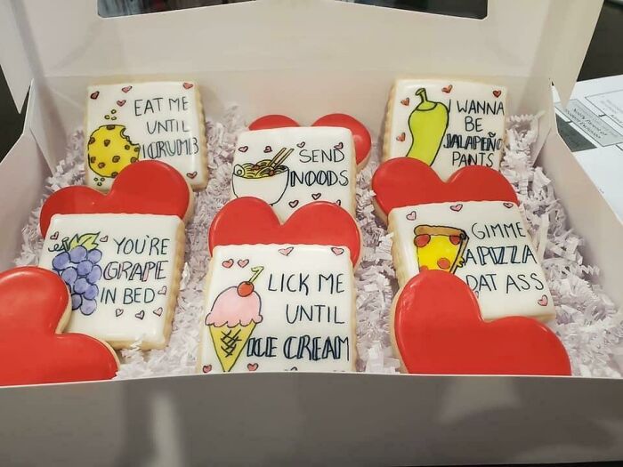 Box of funny Valentine’s Day gifts featuring humorous cookies with playful food puns and red heart shapes.