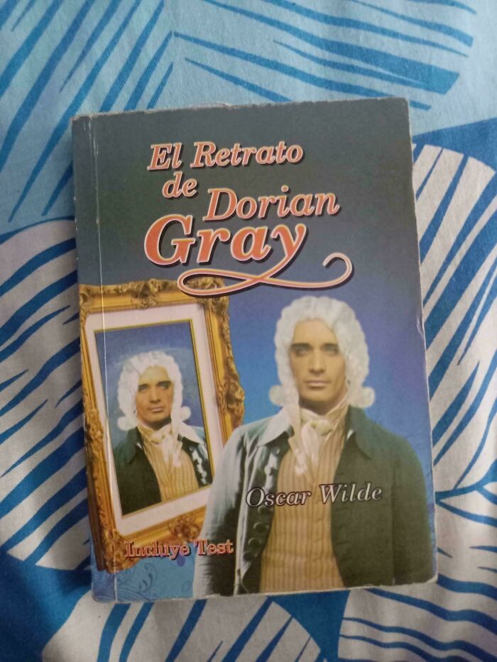 Book cover of El Retrato de Dorian Gray by Oscar Wilde with a poorly rendered portrait and old-fashioned design on a patterned surface.