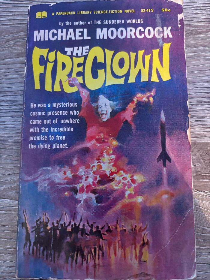 Vintage paperback book cover of The Fireclown by Michael Moorcock, featuring a clown and a crowd with rocket imagery.