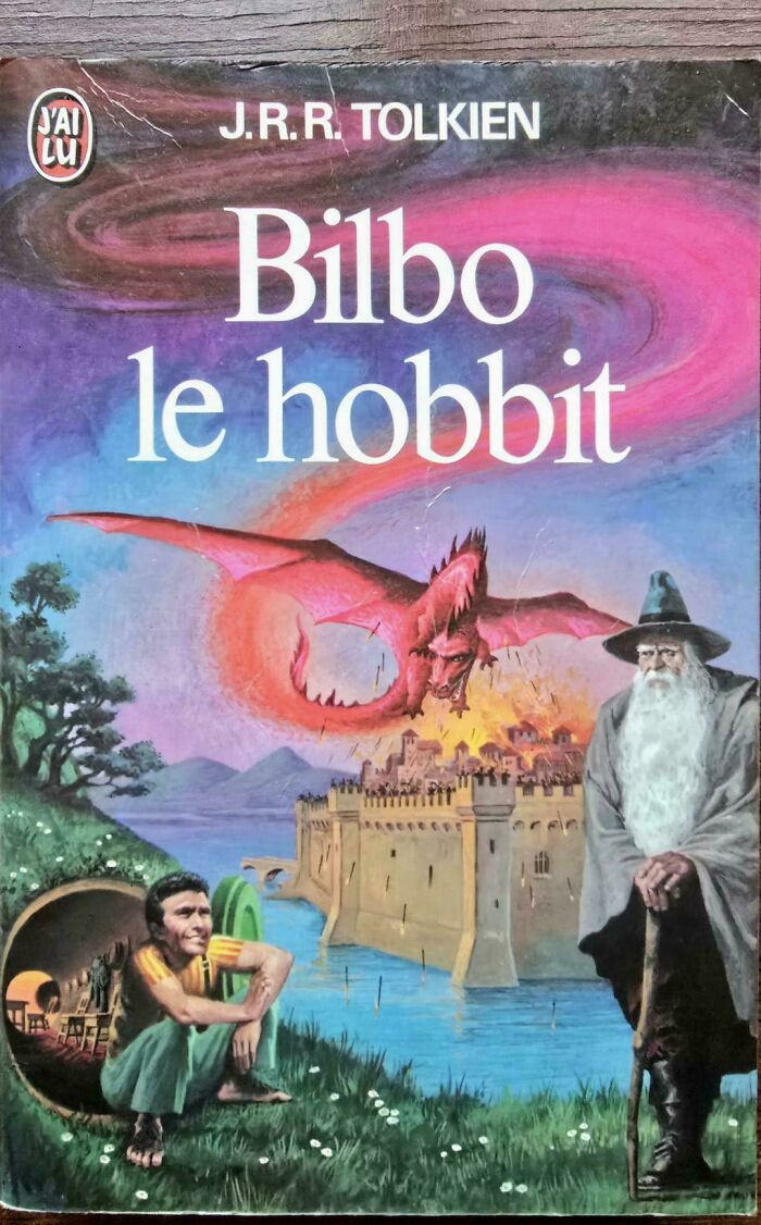 Vintage Bilbo le Hobbit book cover with an awkward dragon, wizard, and hobbit by a castle and river, a terrible book cover example.