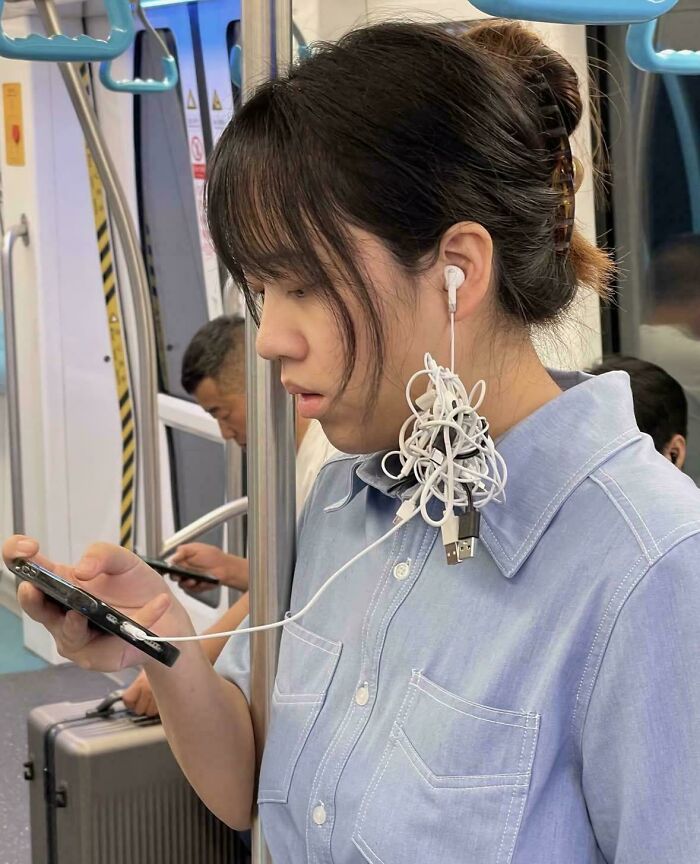 Young woman on public transit with tangled earphones, showing a lazy moment relatable for people needing a day off.