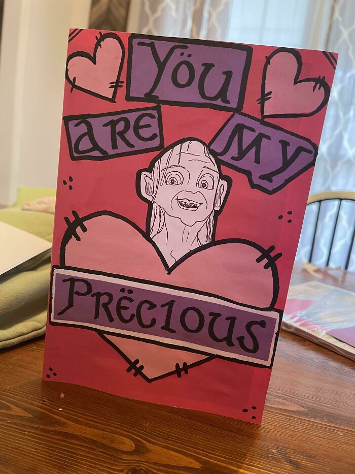 Valentine’s Day gift card with a funny illustration saying you are my precious and hand-drawn hearts on a wooden table.