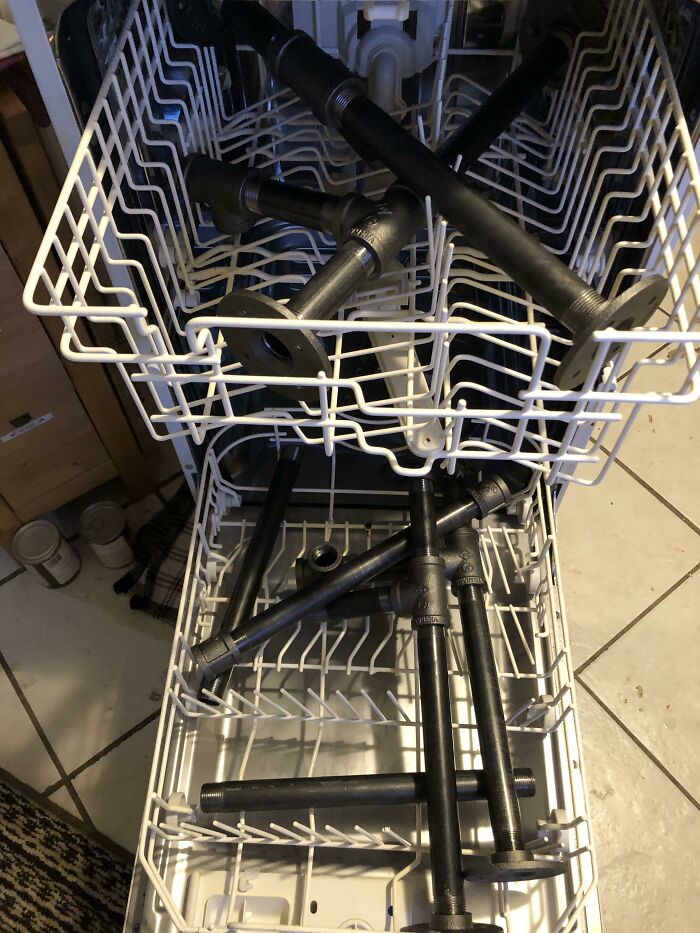 Dishwasher filled with black metal pipes instead of dishes, illustrating extreme laziness and avoiding regular chores.