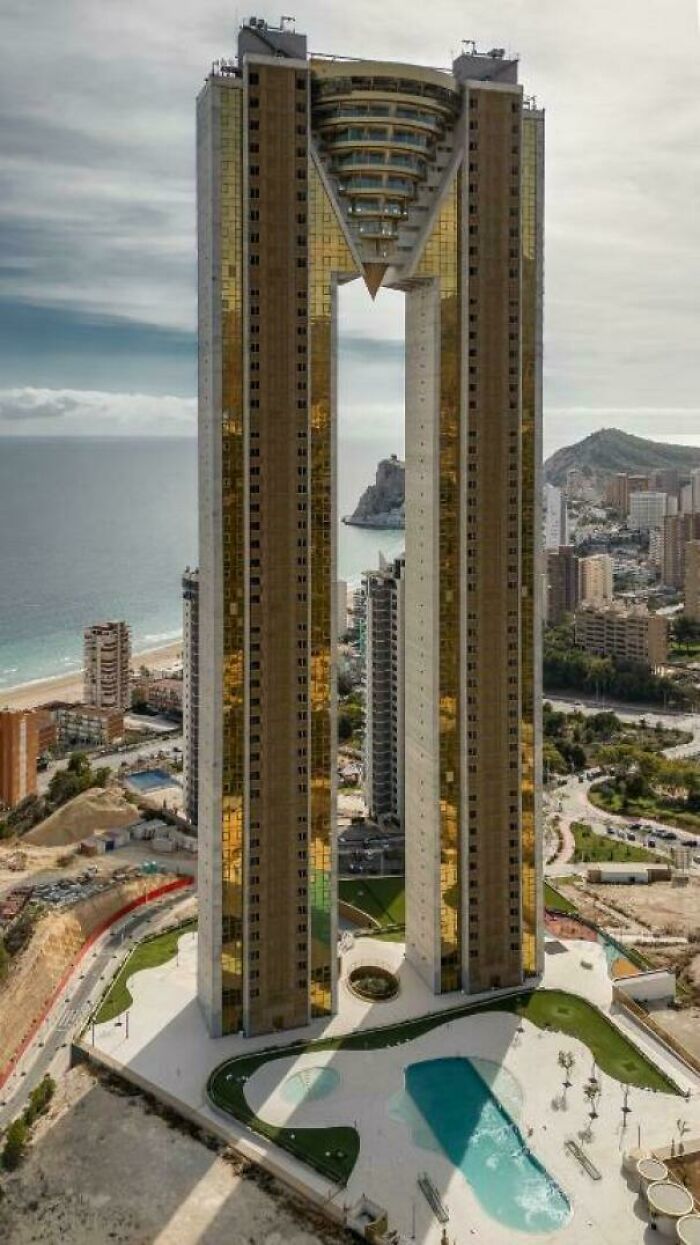 A towering, twin skyscraper with a golden facade and a distinctive archway, a building fit for an evil mastermind's headquarters.