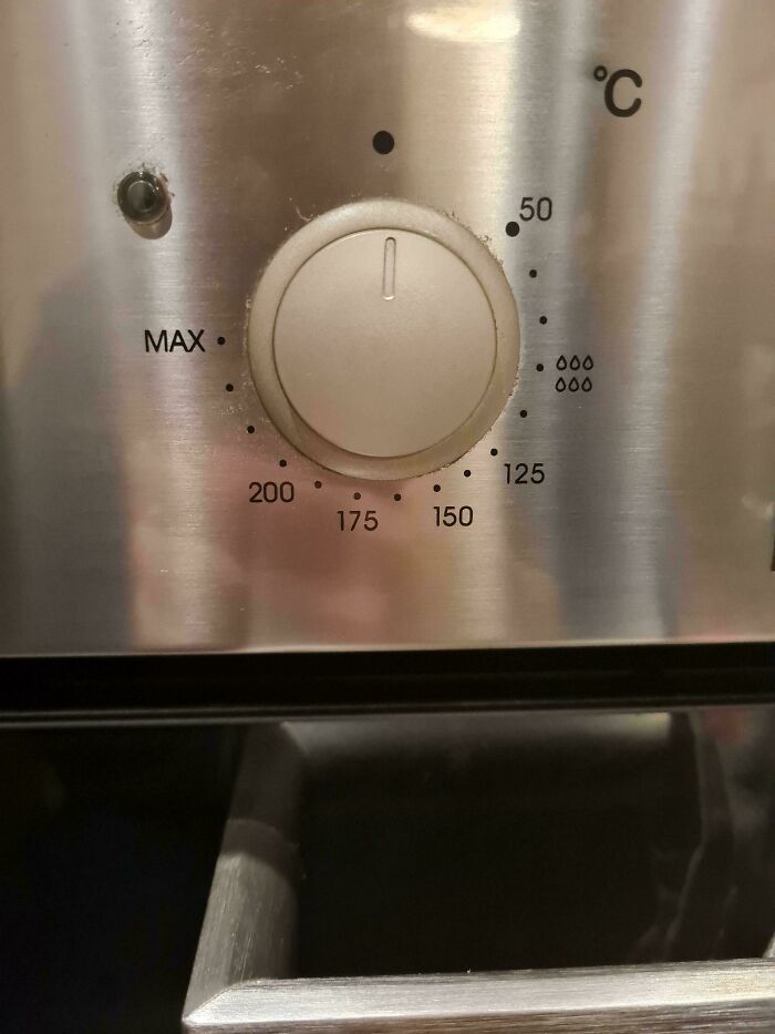 An oven temperature dial with a design fail showing water drops for a higher temperature setting.