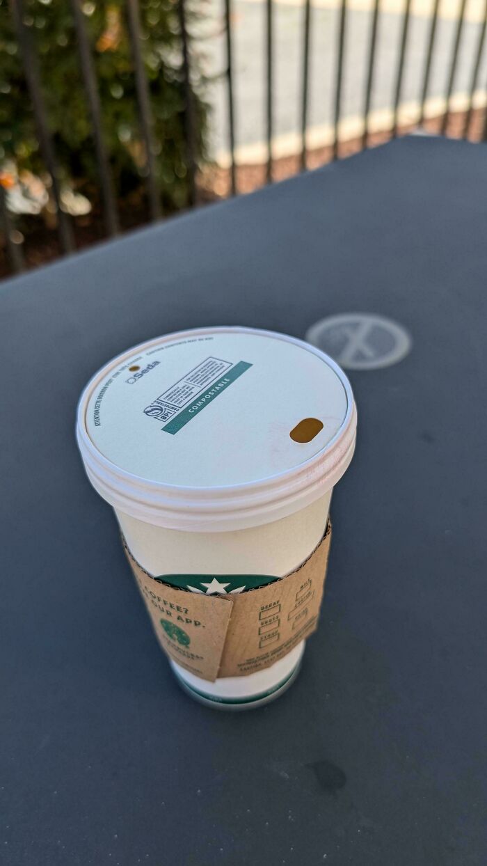 A Starbucks cup with a compostable lid, showcasing a design fail with an unhinged small drinking hole.
