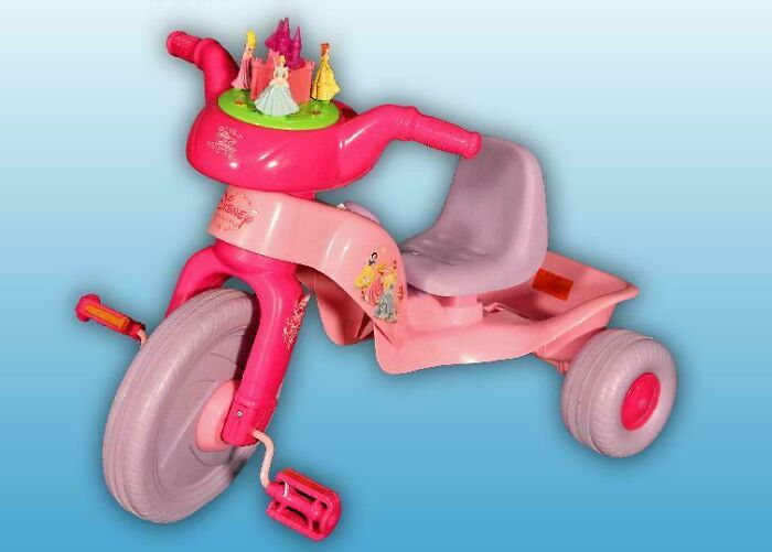 A pink Disney Princess tricycle with a small castle and figures, an unhinged design fail for stability.