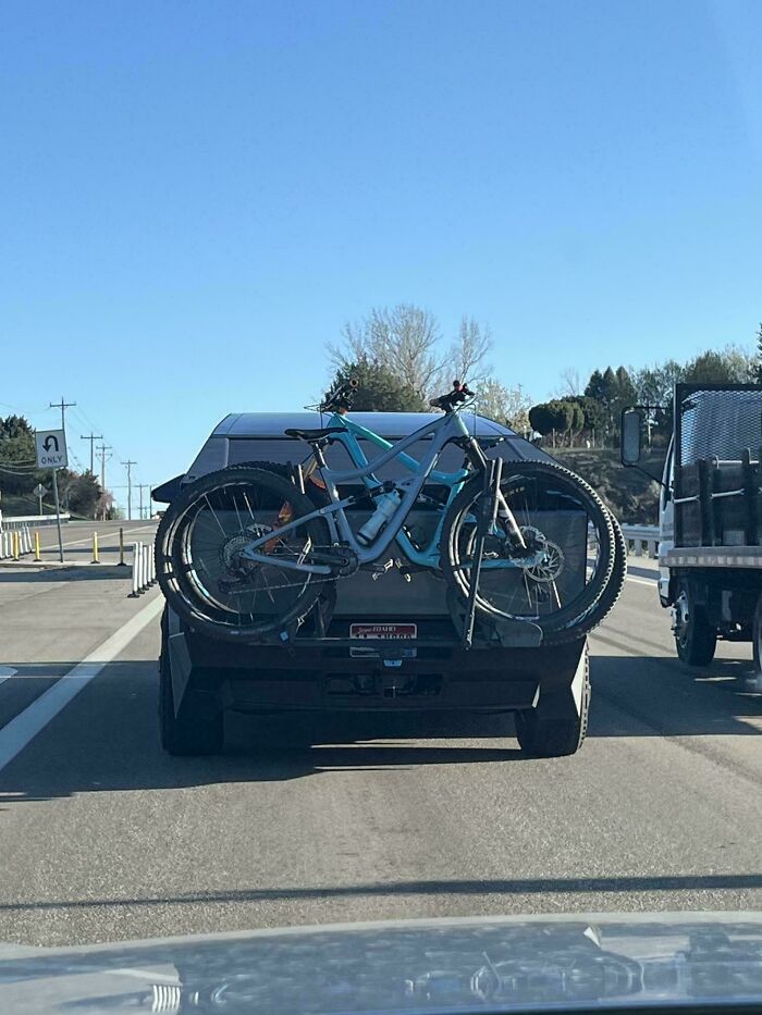 A car on a highway with a bike rack that completely obscures the license plate, a clear design fail.