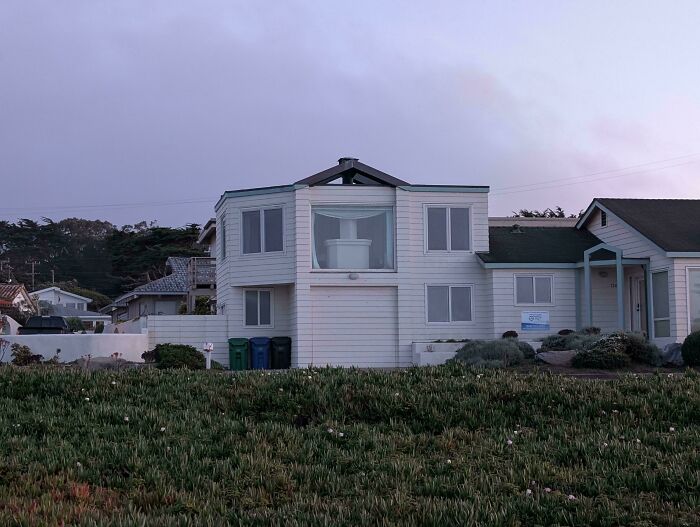 A white two-story house with a unique architectural design and a large bay window, featuring some interesting design fails.