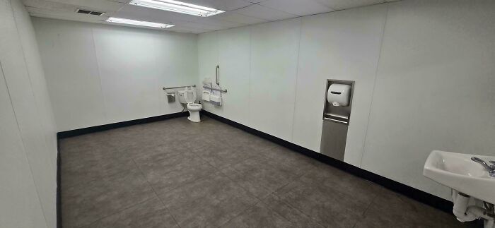A hilariously unhinged design fail: an enormous, empty restroom with a tiny toilet, showcasing a bizarre use of space.