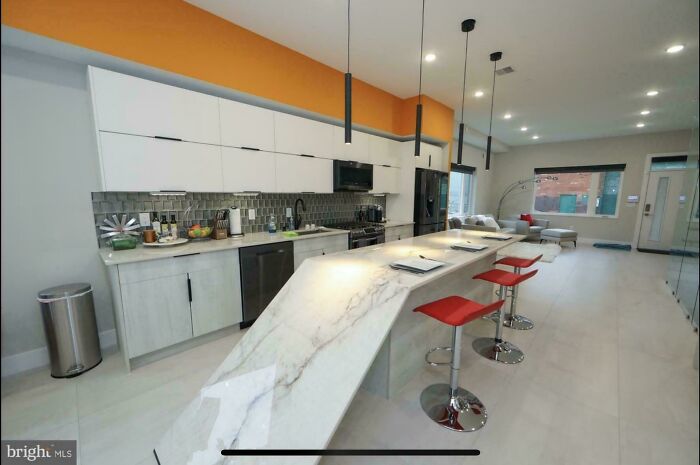 An open-concept kitchen with a long, white marble island, a design fail due to the oddly angled countertop.
