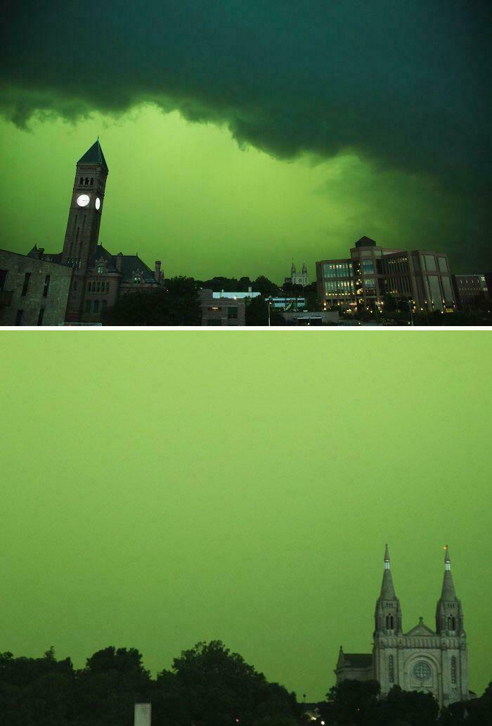 Ominous green storm clouds over city skyline with clock tower and church