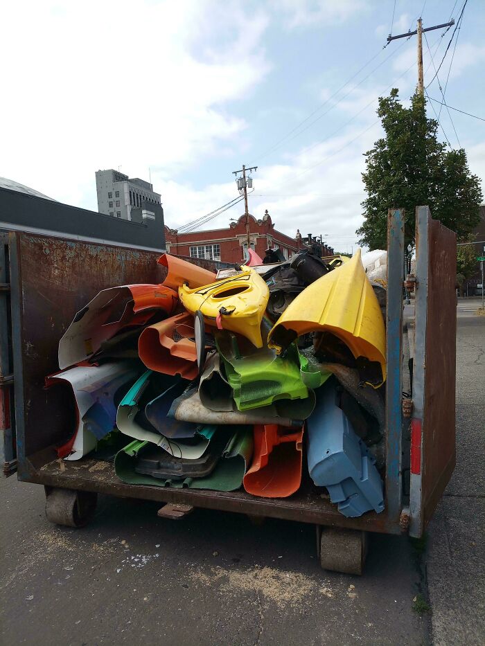 A large dumpster filled with colorful plastic kayak halves, a lucky find from dumpster diving.