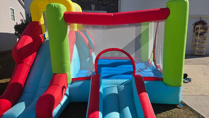 A vibrant, colorful inflatable bounce house with slides found through dumpster diving.