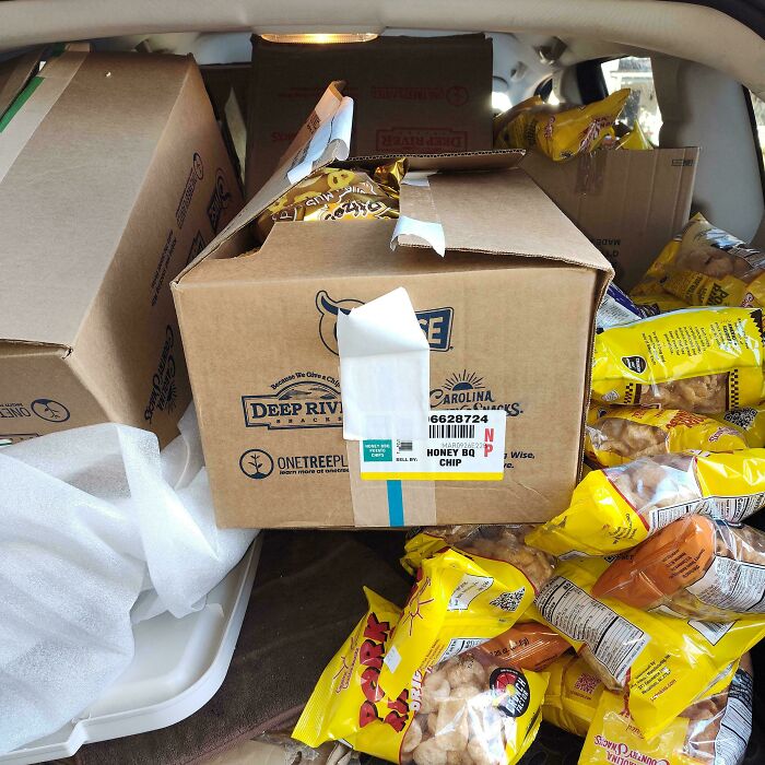 Numerous boxes and bags of snacks in a car trunk, an impressive haul from dumpster diving.