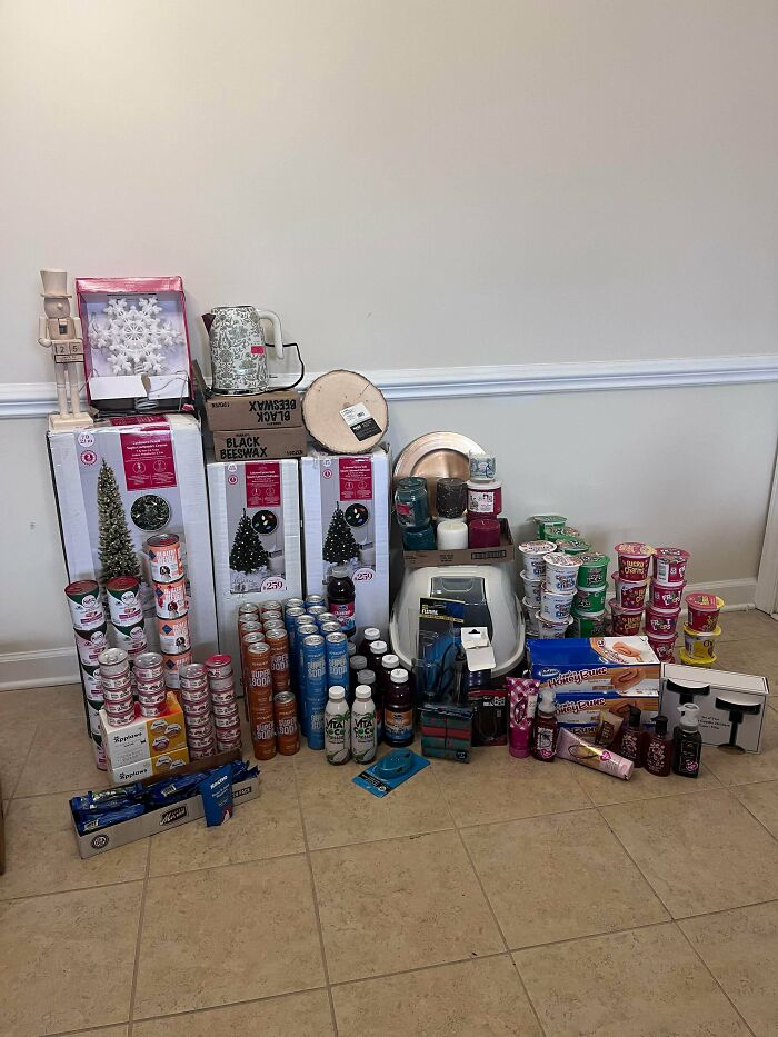 A large haul of dumpster diving finds, including holiday decorations, numerous canned goods, beverages, beauty products, and a cat litter box.