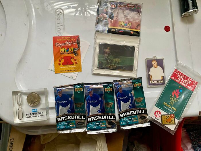 An array of trading cards and memorabilia, including baseball card packs and an Eminem keychain, discovered while dumpster diving.