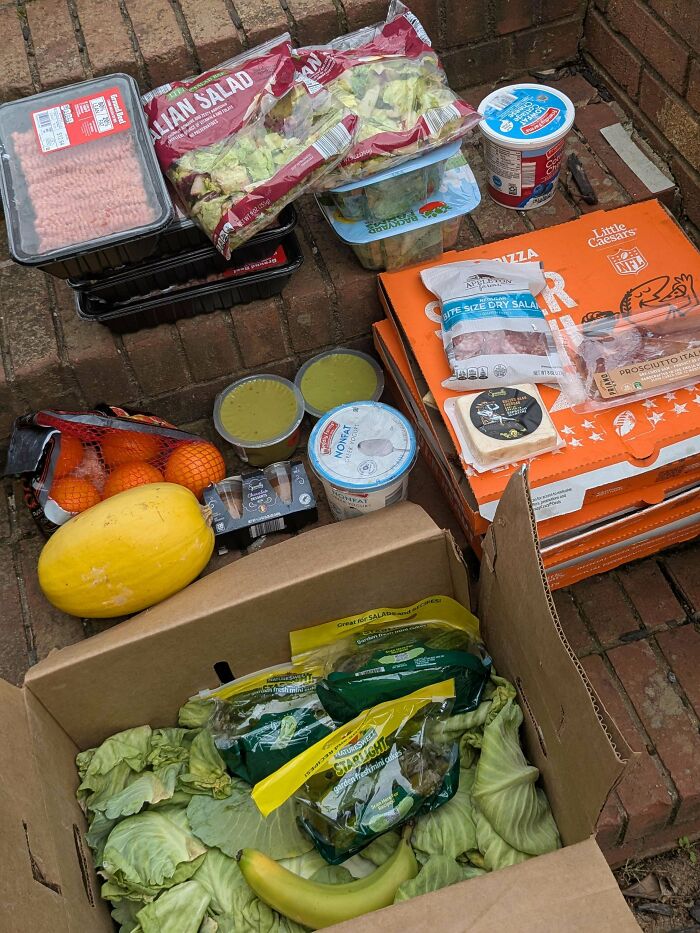 A haul of various food items, including salads, produce, and packaged goods, found while dumpster diving.