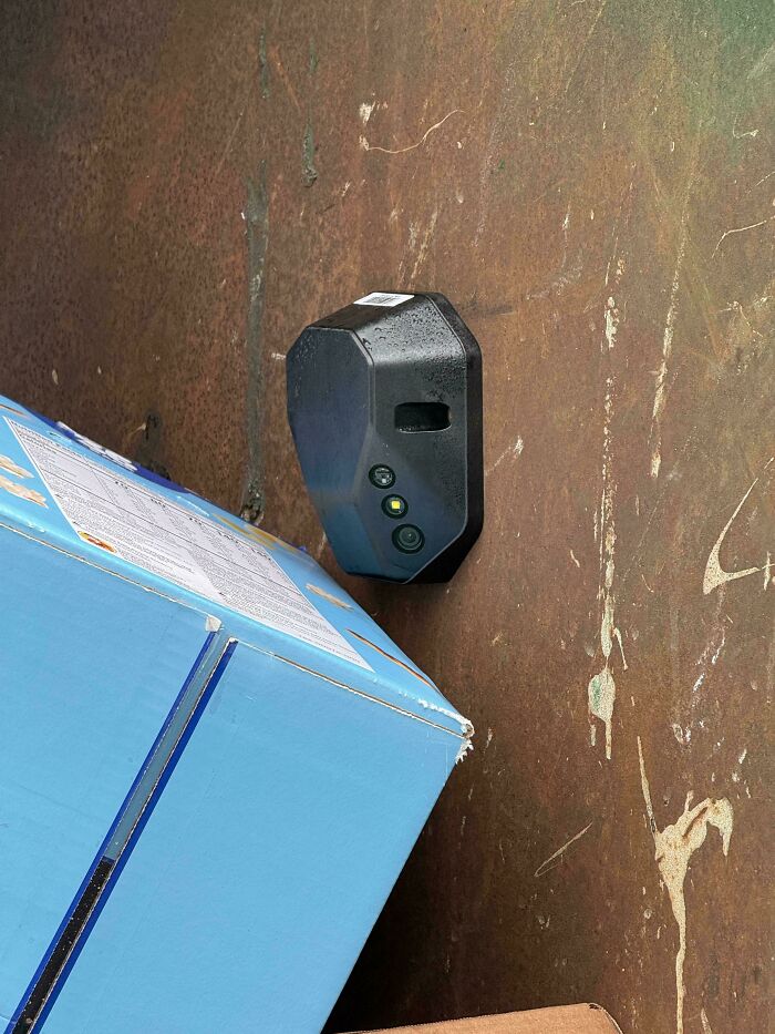 A black electronic device with three yellow lights, and a blue box, found in a dumpster during diving.