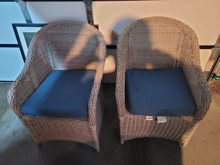 Two wicker chairs with blue cushions, perfect for outdoor seating, discovered during dumpster diving.