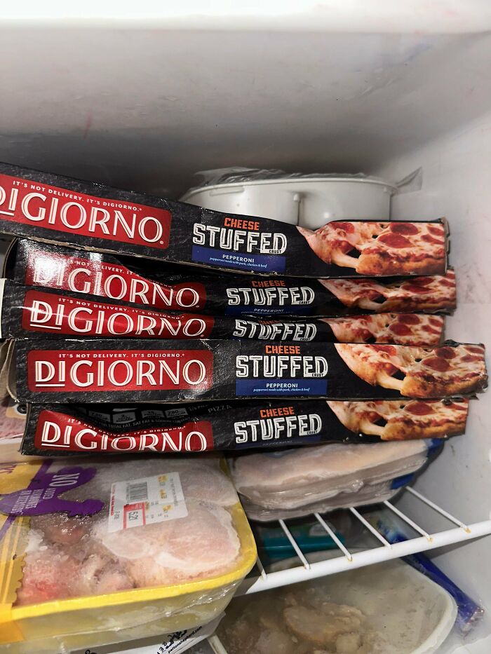 Five boxes of DiGiorno stuffed crust pizzas found while dumpster diving, stacked inside a freezer.