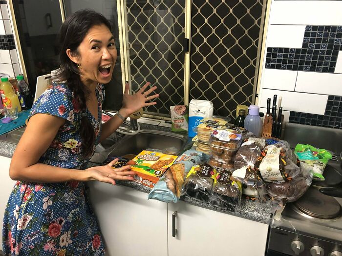 A smiling woman excited about her various food finds, showcasing her luck while dumpster diving.