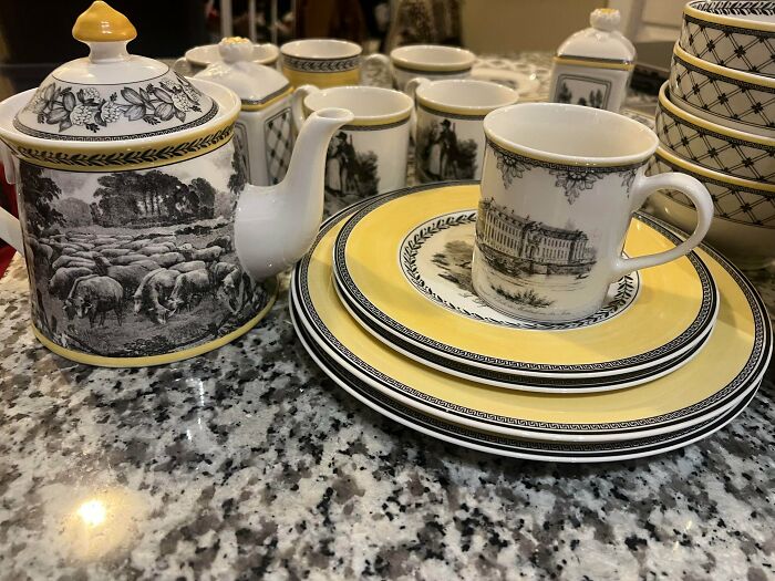 Elegant Buy It For Life dinnerware with yellow borders and detailed black-and-white pastoral and architectural scenes.