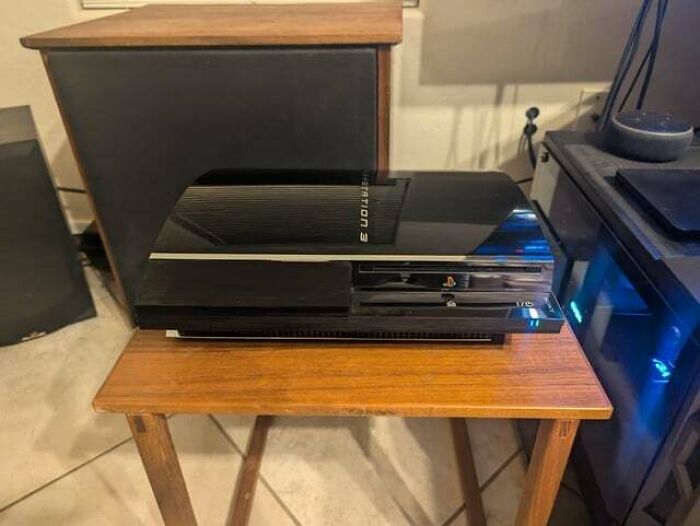 A shiny black Playstation 3 on a wooden side table, demonstrating a Buy It For Life purchase that didn't disappoint.