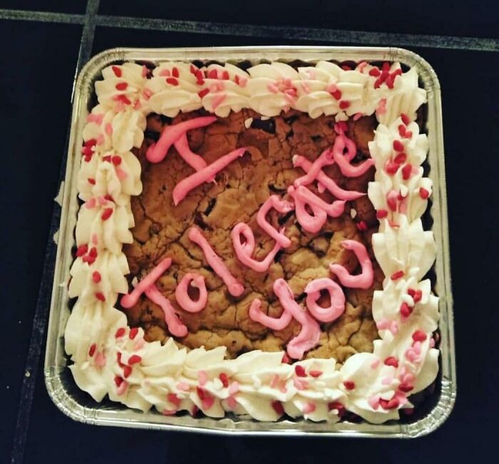 Heart-shaped cookie cake with white frosting and pink icing text, a funny Valentine’s Day gift to show true love.