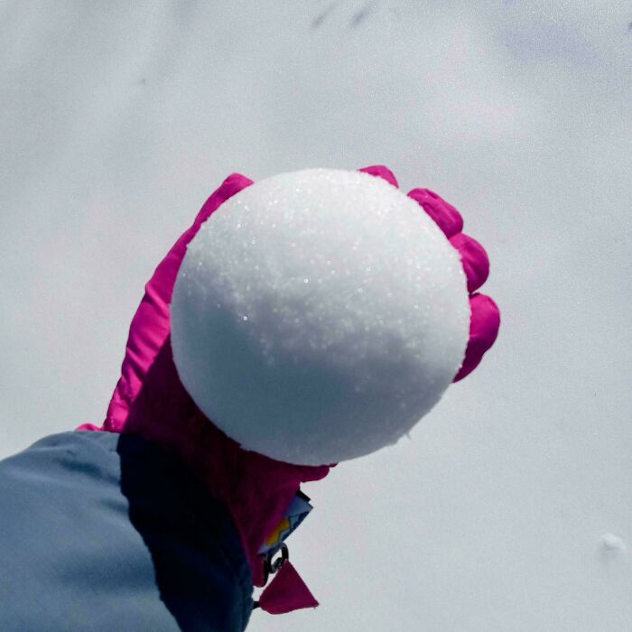 Mildly interesting picture of a perfectly spherical snowball held by a gloved hand.