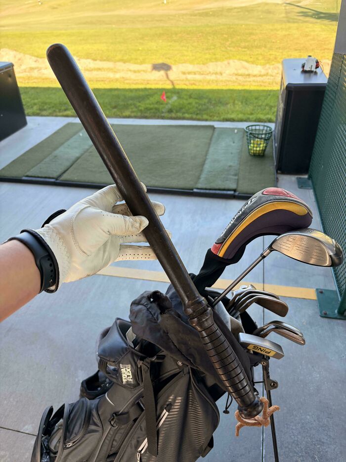 A person holding a golf club that resembles a bat, among other golf clubs, creates a mildly interesting picture.