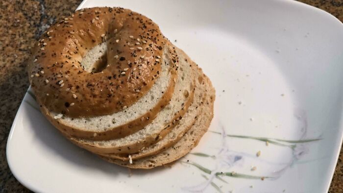 A thinly sliced bagel rests on a white plate, showcasing interesting pictures.