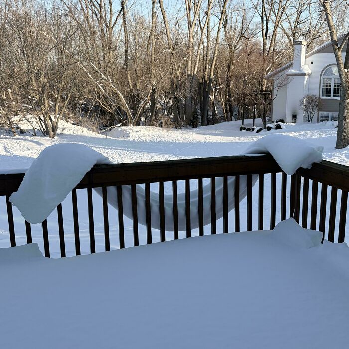 A snow-covered deck with a hammock underneath, creating a mildly interesting picture of winter scenery.