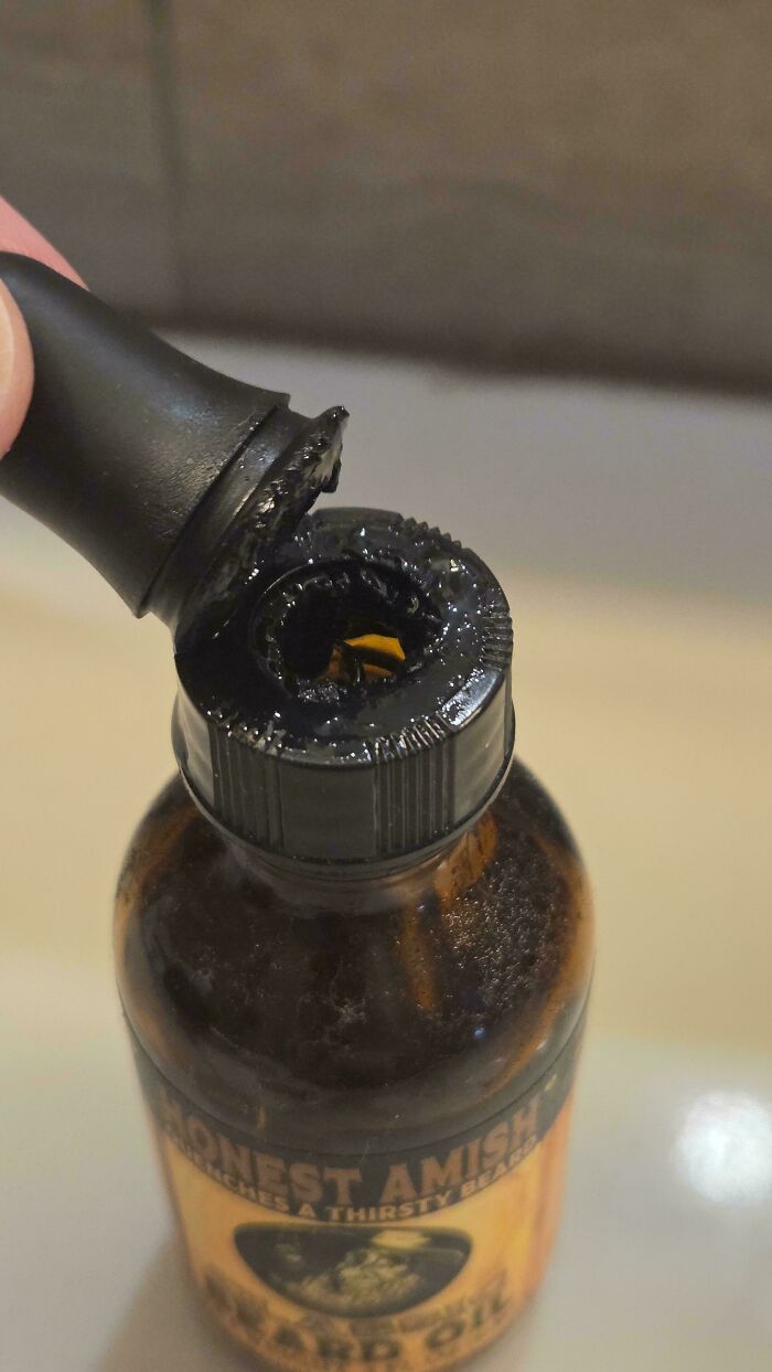 A partially opened bottle of beard oil with the cap broken, a mildly interesting picture.