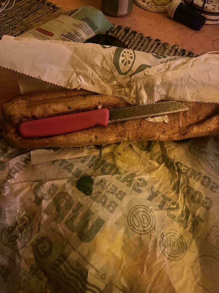 A large sandwich in paper wrapping with a pink-handled knife lying on top, among mildly interesting pictures.