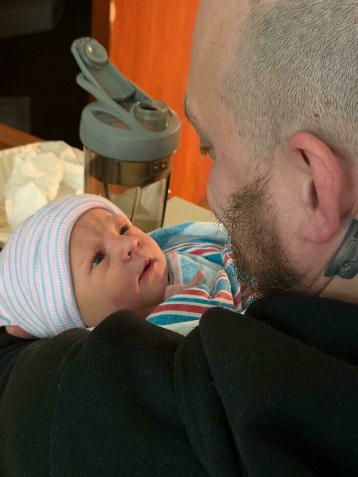 A great dad holding his newborn baby, looking at the baby with love, showcasing what it means to be a great dad.
