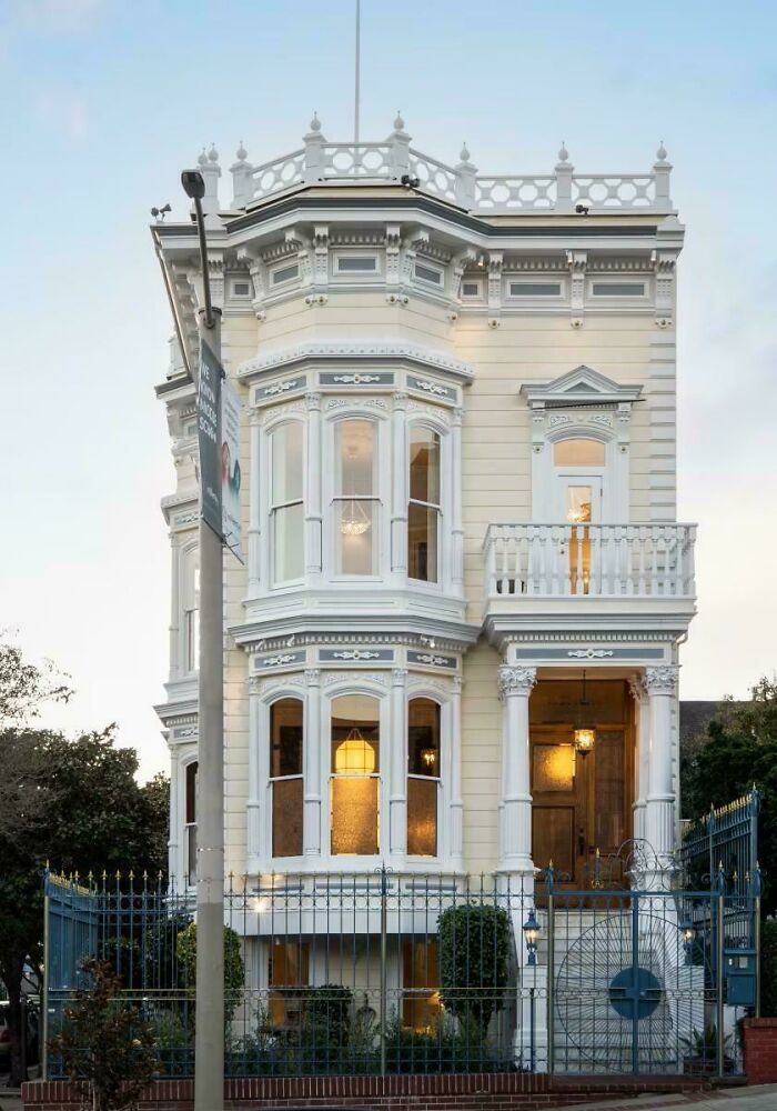 A beautiful example of architecture: a tall, narrow, intricately designed cream-colored building with balconies and bay windows.