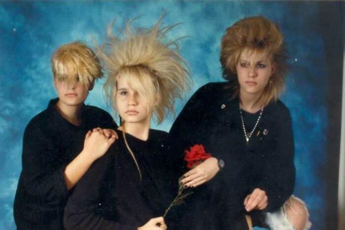 Three people with iconic 80s hairdos featuring voluminous, teased, and spiky styles against a blue backdrop.