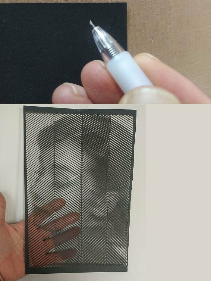 Close-up of hand holding a tool for DIY art creation with a detailed patterned design on black paper.