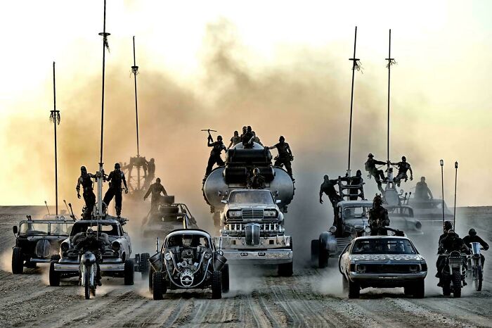 Post-apocalyptic vehicles and characters in a high-speed chase scene from a movie with absurd yet accurate movie details.