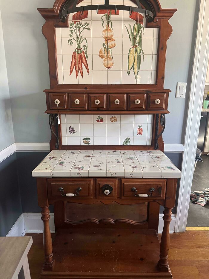 An antique wooden hutch with tiled surfaces featuring vegetable designs, a unique thrift store jackpot.