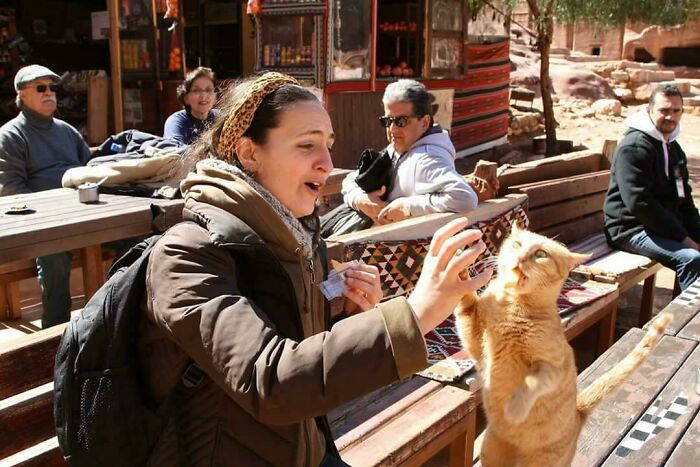 Woman interacting with a cat outdoors, capturing a spontaneous moment in a photo better than expected.