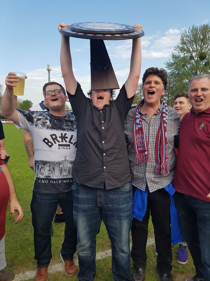 Group of men celebrating outdoors with one holding a trophy in a funny photo that turned out way better than expected.