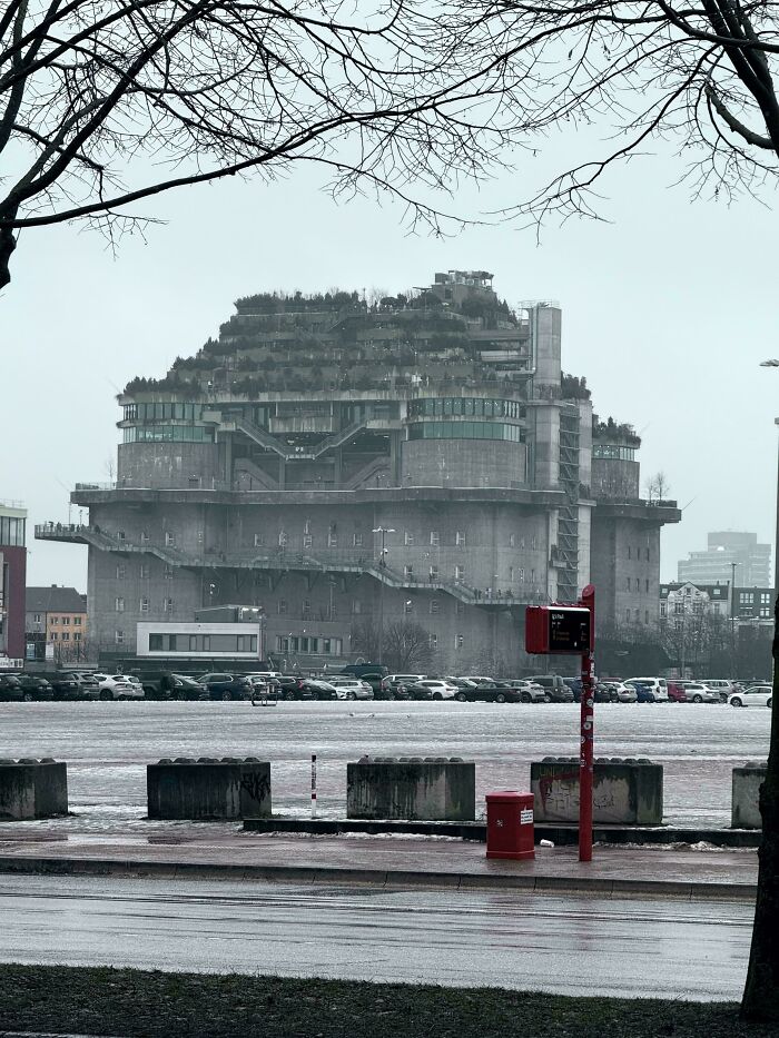 A massive, concrete building with multiple levels and greenery on top, looking like a stronghold for an evil mastermind.