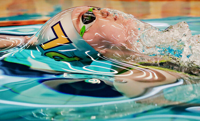 Swimmer captured underwater with perfect timing, creating a striking and unexpected photo with water reflections.
