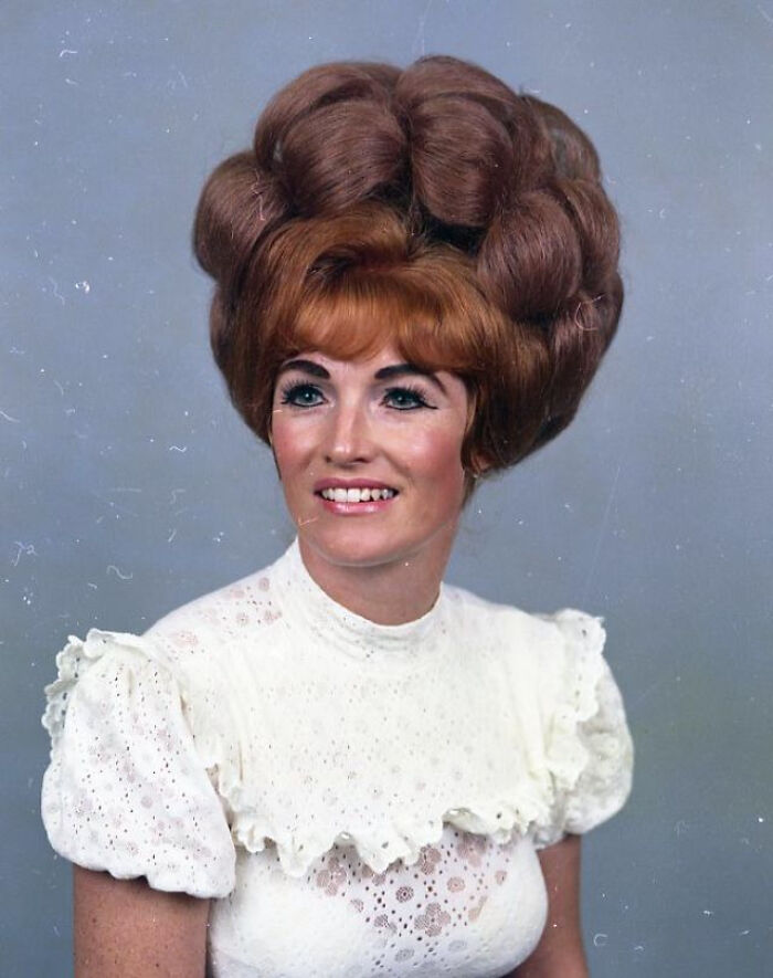 Candid old photo of a woman with a large, elaborate hairstyle and a white lace top, revealing what the world looked like generations ago.